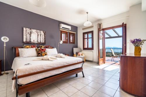 a bedroom with a large bed and a balcony at Kumusha Villa near Fiscardo in Mánganos