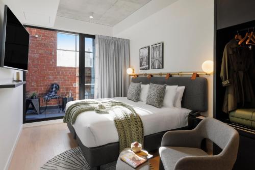 sypialnia z łóżkiem, krzesłem i kanapą w obiekcie Veriu Collingwood w Melbourne