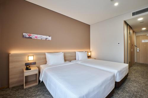a hotel room with a large white bed with two pillows at Sotetsu Grand Fresa Saigon in Ho Chi Minh City