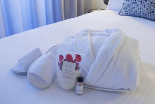 a bed with a white blanket and a bottle of medicine at Veriu Collingwood in Melbourne