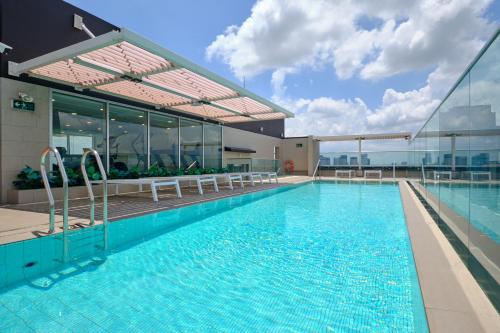 a swimming pool with tables and chairs in a building at Sotetsu Grand Fresa Saigon 相鉄グランドフレッサ サイゴン in Ho Chi Minh City