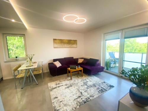 ein Wohnzimmer mit einem lila Sofa und einem Tisch in der Unterkunft Apartament pod Świerkami in Chojniczki