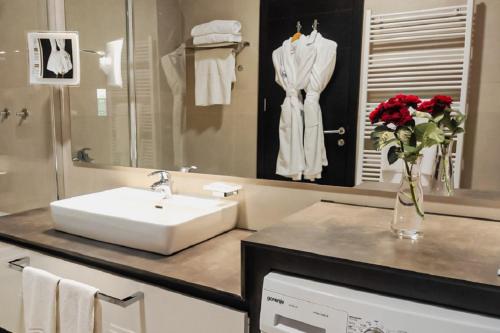 a bathroom with a sink and a vase with red roses at Bosmal Arjaan by Rotana in Sarajevo