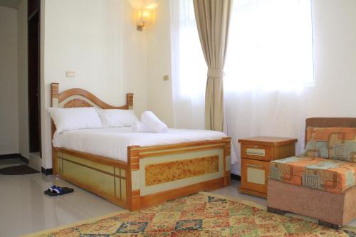 a bedroom with a bed and a chair and a window at Avi Guest House in Addis Ababa