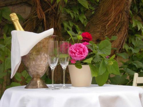 a table with wine glasses and a vase with a flower at SchlossparkFerienwohnungen Rheinsberg mit Garten in Rheinsberg