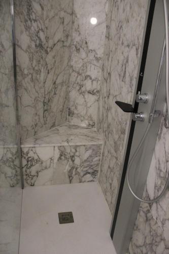 a bathroom with a shower with a marble wall at Il Giardino della Scuncerta in Lecce
