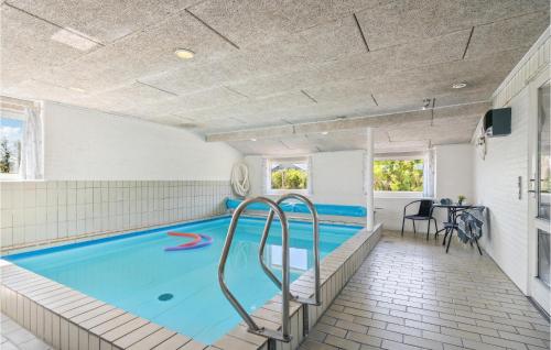 a swimming pool in a room with a table and chairs at Amazing Home In Ringkøbing With Sauna in Ringkøbing