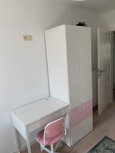 a desk with a pink chair next to a white cabinet at Appartement au centre d'une ville historique. in Bastogne