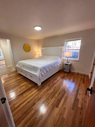 a bedroom with a white bed and a wooden floor at The Alfred, Downtown Chehalis in Chehalis