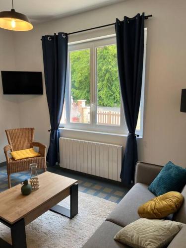 ein Wohnzimmer mit einem Sofa, einem Tisch und einem Fenster in der Unterkunft Chez Mimi, la route des fruits in Jumièges