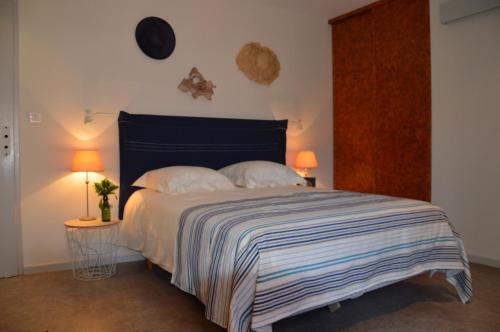 ein Schlafzimmer mit einem Bett mit einer blau-weißen gestreiften Decke in der Unterkunft Moulin de la Cuse - L'îlote in Cusance