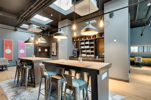 a bar in a restaurant with stools and lights at Premier Inn Wolfsburg City Centre in Wolfsburg