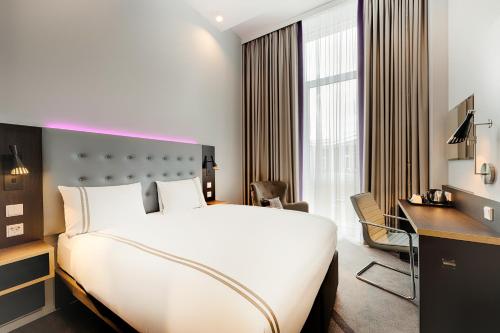 ein Hotelzimmer mit einem großen Bett und einem Schreibtisch in der Unterkunft Premier Inn Wolfsburg City Centre in Wolfsburg