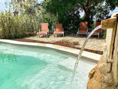 a pool with two chairs and a water fountain at Asis de Marratxinet in Marratxí 