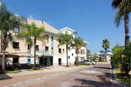 a building with palm trees in front of a street at Hotel Premiere in Marina di Varcaturo