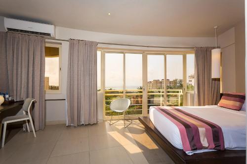 a bedroom with a bed and a desk and windows at Bliss Resort in Nyali