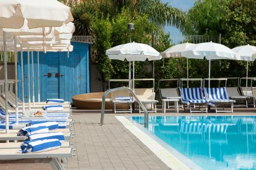a pool with blue and white chairs and umbrellas at Hotel Premiere in Marina di Varcaturo