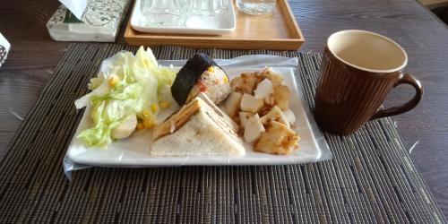 einen Teller mit einem Sandwich und Salat sowie eine Tasse Kaffee in der Unterkunft Guiju Lin Garden Homestay in Nanzhuang