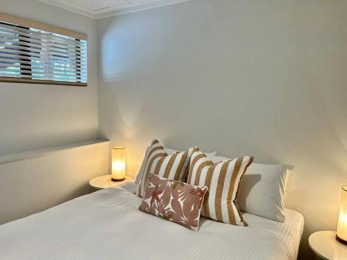 a bedroom with a bed with pillows and a window at Rosella - Bushland Hideaway in Yallingup