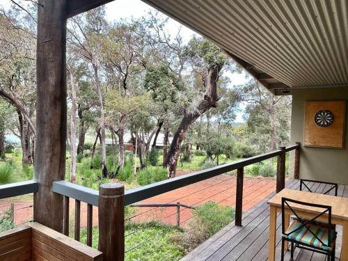 a porch with a table and chairs and trees at Rosella - Bushland Hideaway in Yallingup