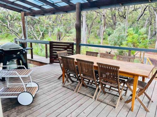 a wooden table and chairs on a deck with a grill at Rosella - Bushland Hideaway in Yallingup