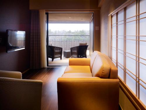 a living room with a couch and a large window at Laforet Shuzenji Sanshisuimei in Izu