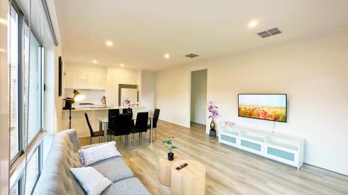 a living room with a couch and a tv on a wall at The Grove Home by GoodLive in Tarneit