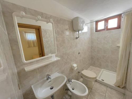 een badkamer met een wastafel, een toilet en een spiegel bij Le camerine in Cecina