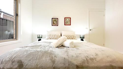 a white bedroom with a large bed with two pillows at The Grove Home by GoodLive in Tarneit