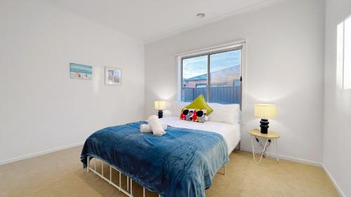 a white bedroom with a bed and a window at The Grove Townhouse by GoodLive in Tarneit