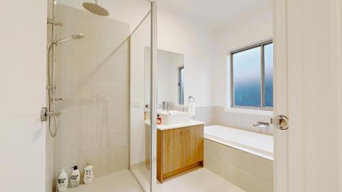 a bathroom with a shower and a sink and a mirror at The Grove Townhouse by GoodLive in Tarneit