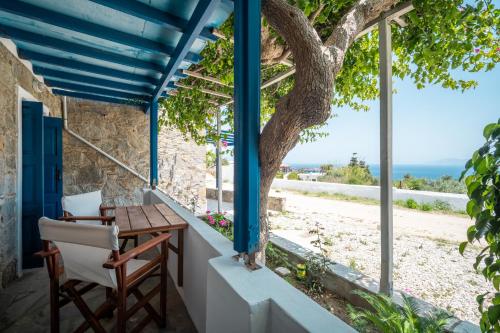 eine Veranda mit einem Tisch, Stühlen und einem Baum in der Unterkunft Niel Serifos in Serifos Chora