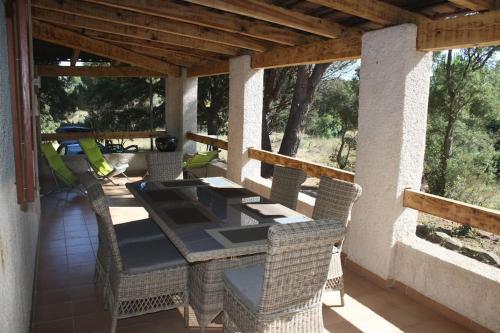 un patio avec une table et des chaises sur un porche dans l'établissement QUIET COTTAGE NEAR CITY CENTER, à Porto-Vecchio