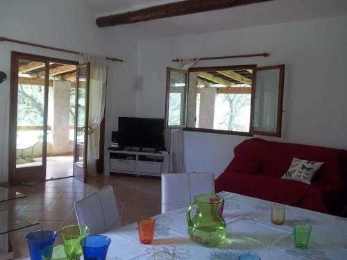 un salon avec une table et un canapé rouge dans l'établissement QUIET COTTAGE NEAR CITY CENTER, à Porto-Vecchio