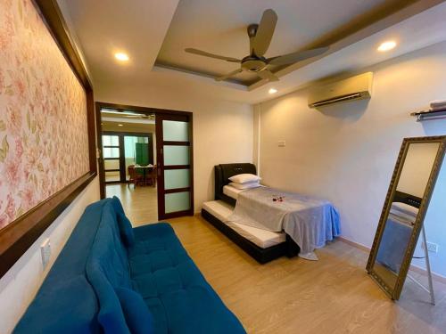 a living room with a blue couch and a bed at Platinum Homestay in Batu Caves