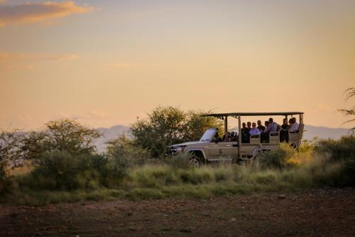Un groupe de personnes circulant à l'arrière d'un camion dans l'établissement Okapuka Safari Lodge, à Windhoek