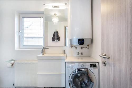 - une cuisine blanche avec un lave-linge et un évier dans l'établissement Ljubljana sLOVEnia + FREEparking & Bikes, à Ljubljana