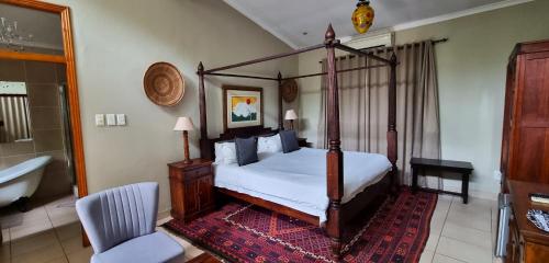 a bedroom with a four poster bed and a chair at African Roots Guest House - No Loadshedding in Polokwane