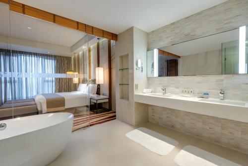 uma casa de banho com uma banheira, um lavatório e uma cama em Holiday Inn Shanghai Hongqiao, an IHG Hotel em Xangai