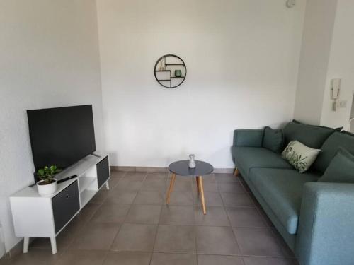 a living room with a green couch and a tv at Appartement 2 personnes in Trets