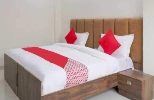 1 cama con sábanas rojas y blancas y cabecero de madera en Flagship Leisurrestay, en Nueva Delhi