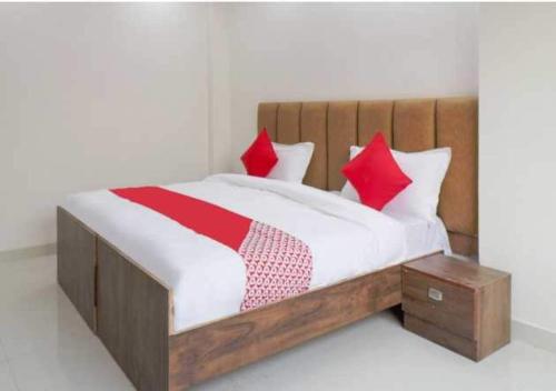 1 dormitorio con cama con almohadas rojas y marco de madera en Flagship Leisurrestay, en Nueva Delhi