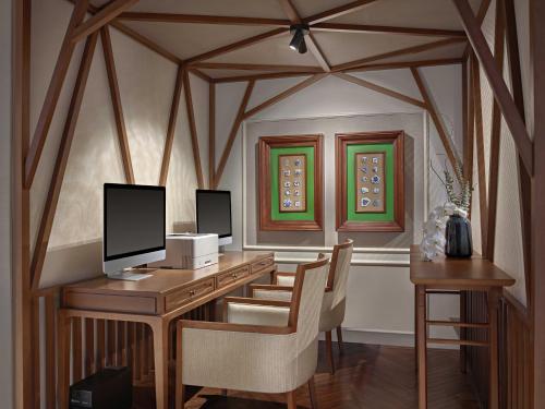 a room with a desk with a computer and chairs at Grand Mercure Hanoi in Hanoi
