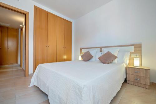 1 dormitorio con cama blanca y armario de madera en Sara, en L'Aldea