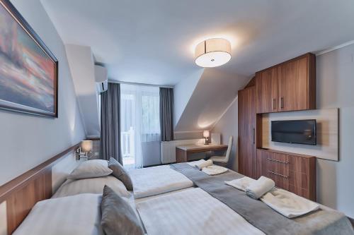 a bedroom with two beds and a flat screen tv at Tokajer Wellness Panzió in Keszthely