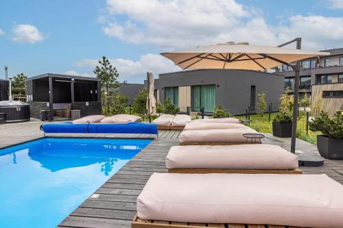 a row of pillows and an umbrella next to a pool at Stella maris mano jura 2 Kunigiskiai in Palanga