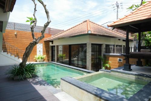 a villa with a swimming pool in front of a house at Bugan Villas in Seminyak