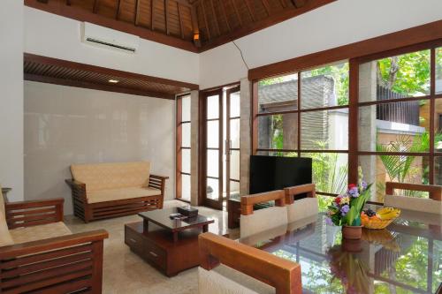 a living room with a couch and a television at Bugan Villas in Seminyak