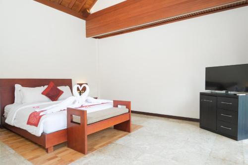 a bedroom with a bed and a flat screen tv at Bugan Villas in Seminyak