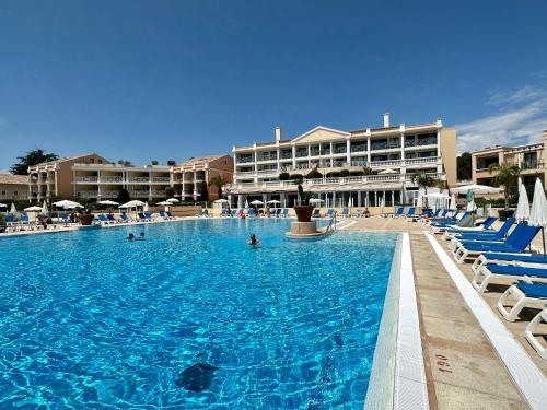 une grande piscine avec des chaises bleues et un hôtel dans l'établissement Beau T2 avec terrasse vue mer, à Cannes